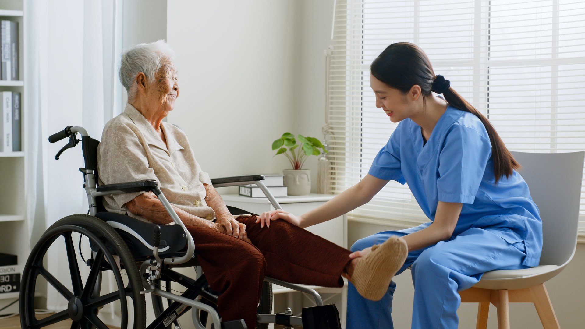 Young Asian woman nurse, caregiver assist a senior Asian woman to do physical therapy and exercise leg at home.