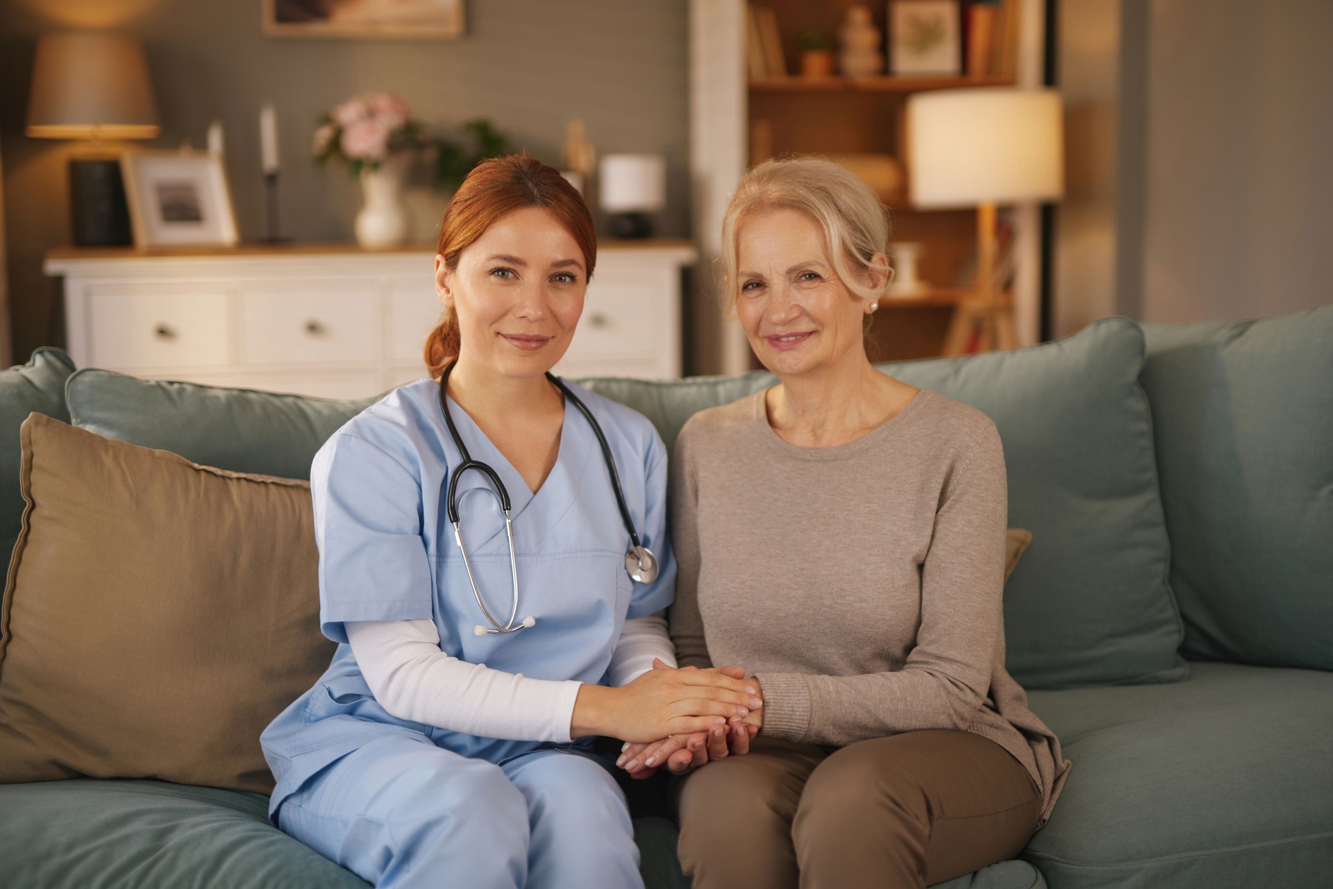 Nurse holding hands of senior woman, providing home care and support